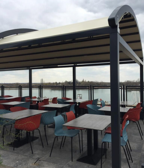 Pergola εξωτερικού χώρου με τραπέζια και καρέκλες, ιδανική για χαλάρωση και φαγητό με θέα στη λίμνη.